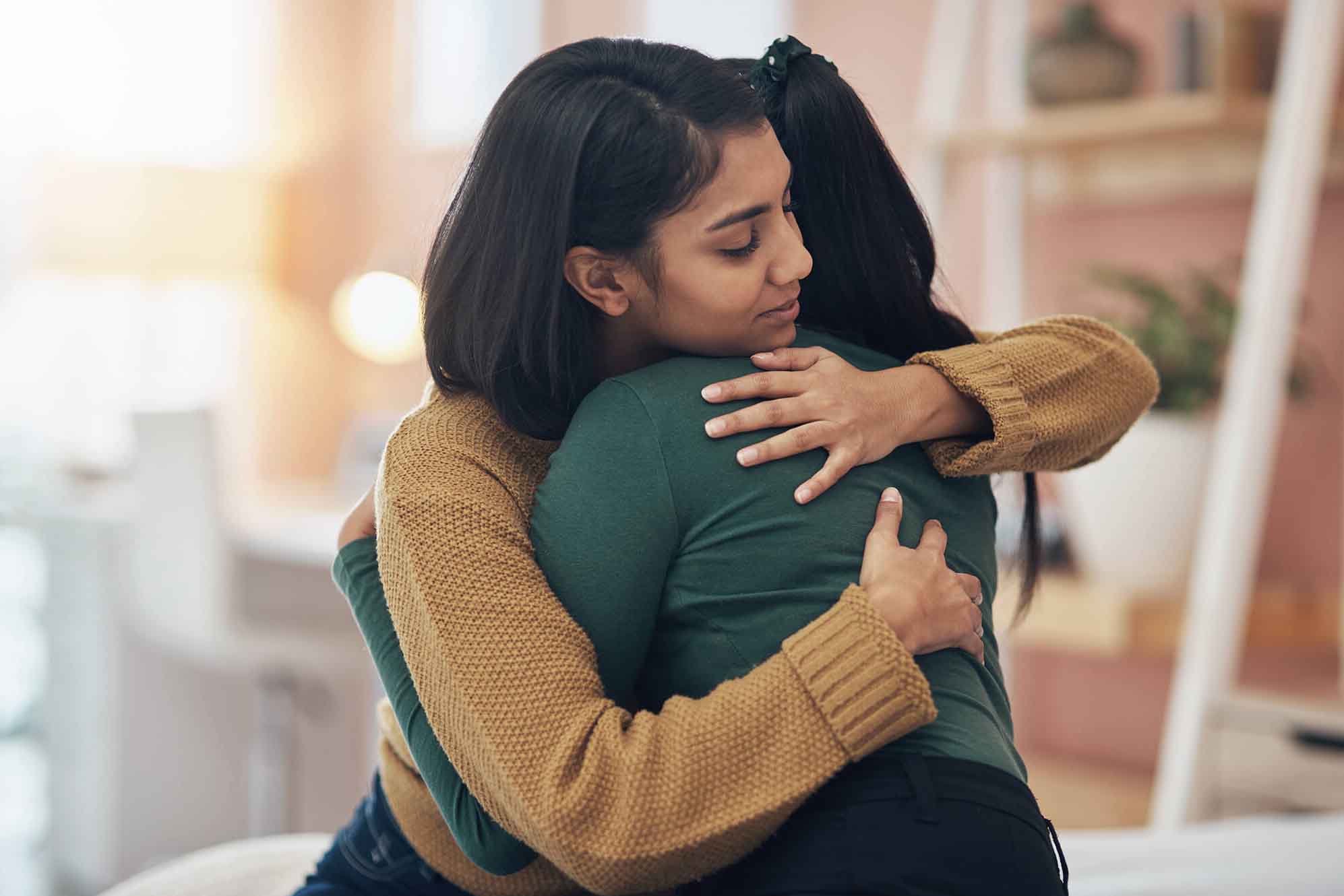 Two women embracing each other at home